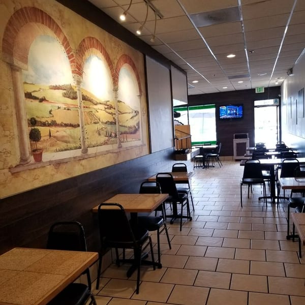 Interior of Pita's Mediterranean Grill with tables, chairs, and a large mural of a Mediterranean landscape.