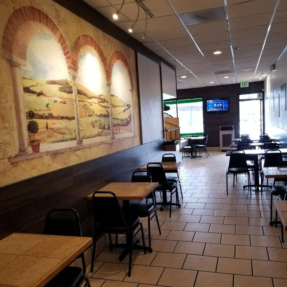 Interior of Pita's Mediterranean Grill with tables, chairs, and a large mural of a Mediterranean landscape.