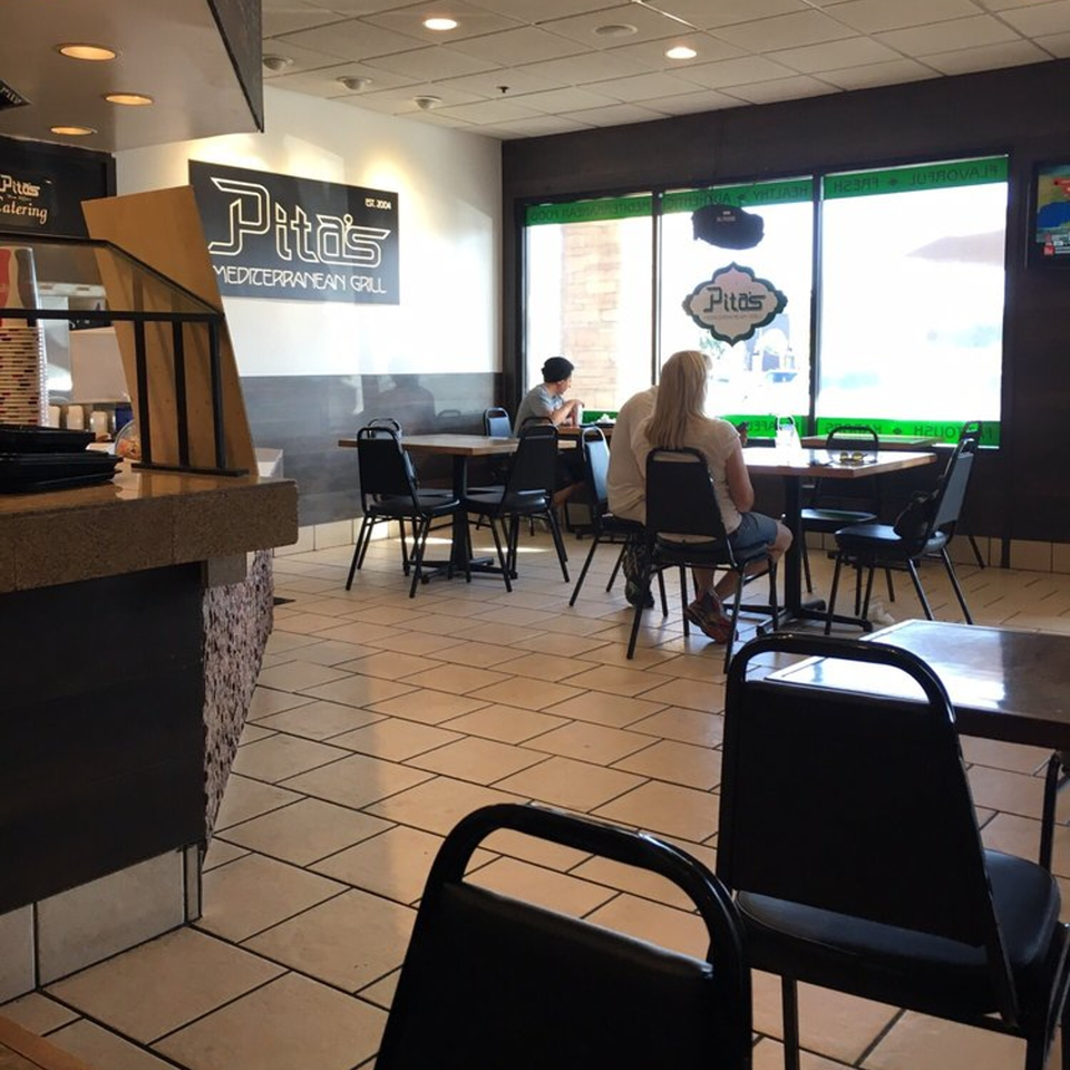 Interior of Pita's Mediterranean Grill with customers seated at tables near large windows.